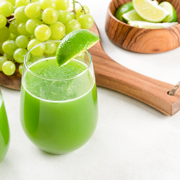 glass of green limeade juice on a white surface