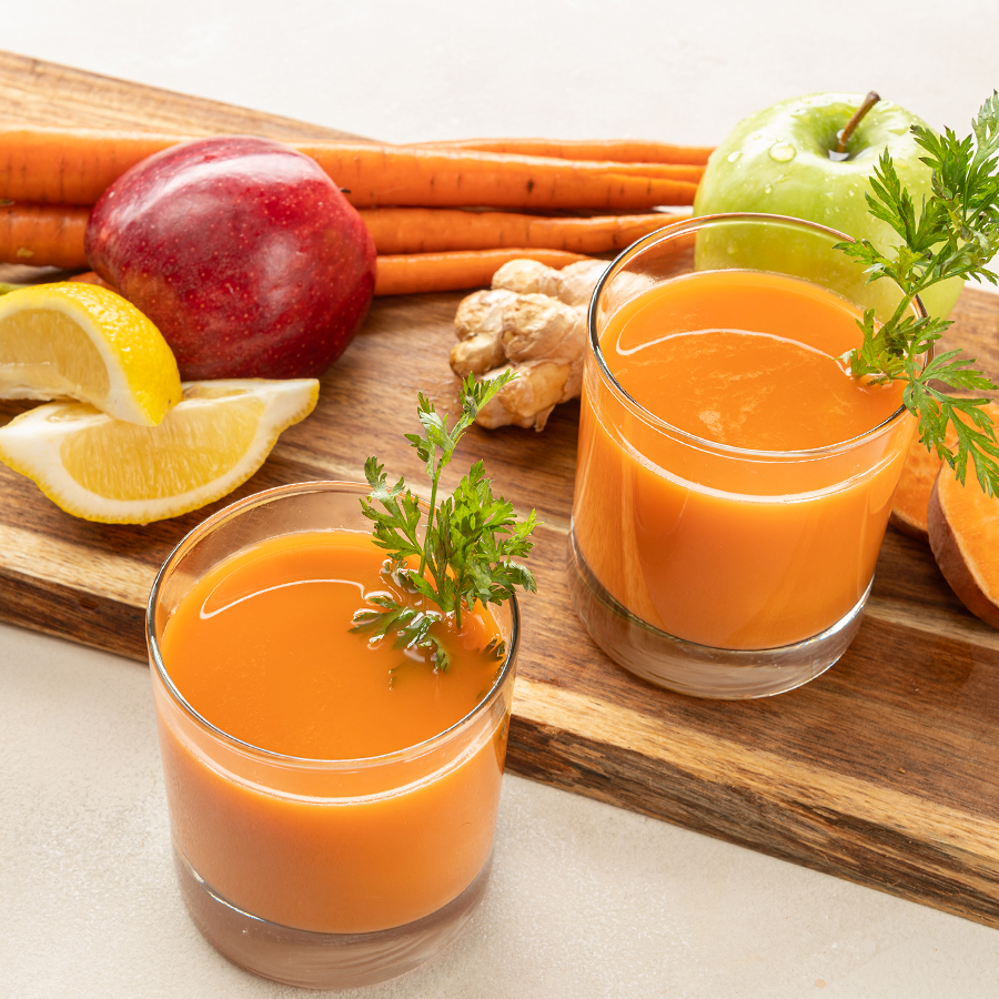 two glasses of sweet potato juice with ingredients on a cutting board