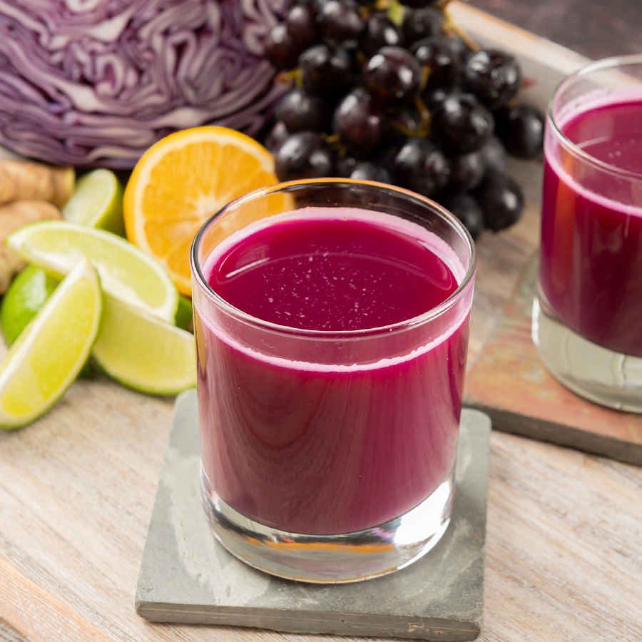two glasses of red cabbage juice on a wooden tray