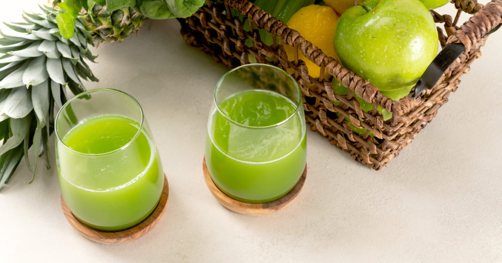 dos vasos de jugo verde antiinflamatorio en una mesa blanca
