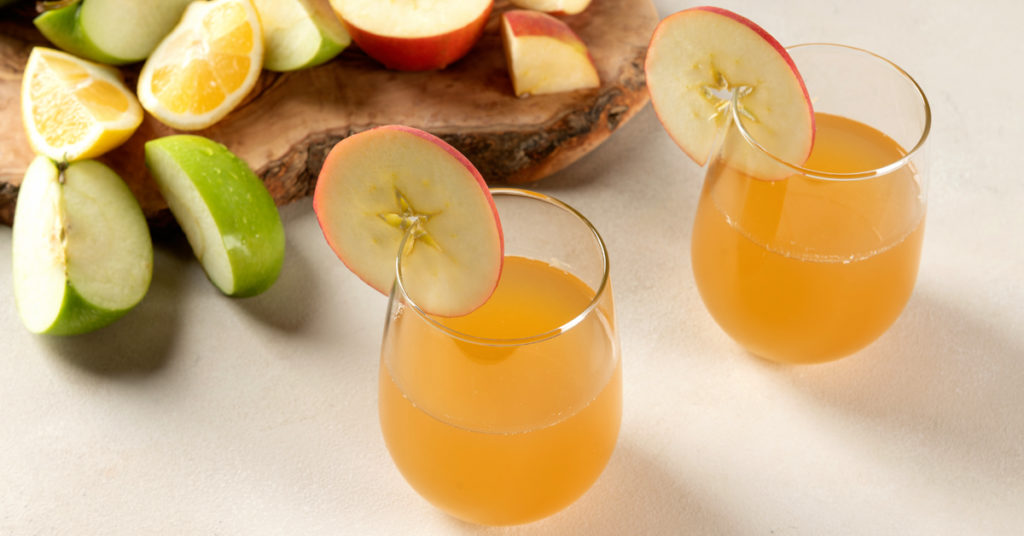  deux verres de recette de jus de pomme maison sur une table blanche 