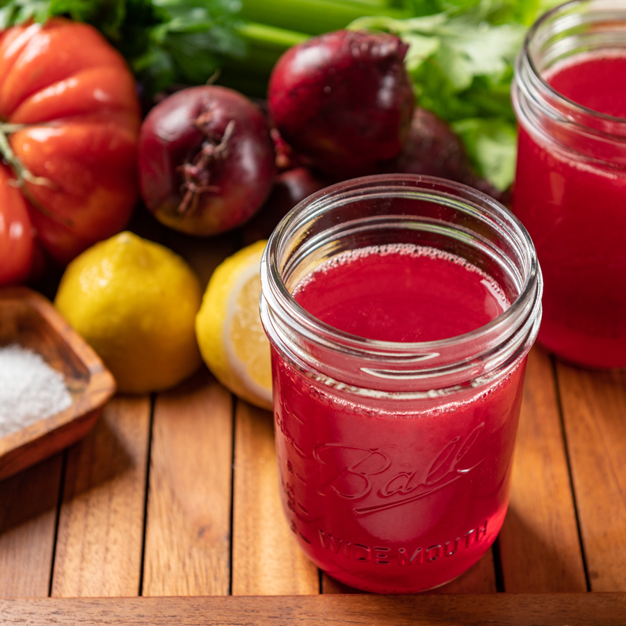 jar of tomato juice with ingredients to make the recipe on a wooden tray