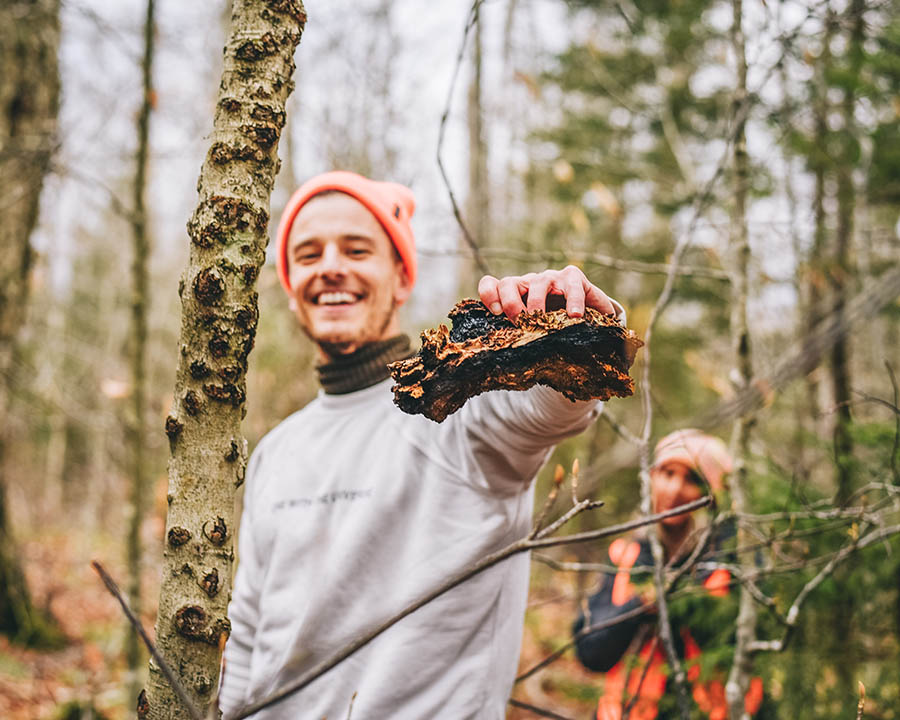 man holding a piece of chaga in the woods